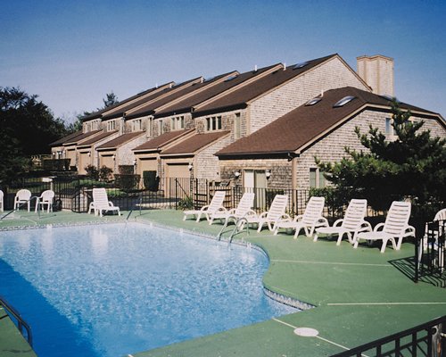 An outdoor swimming pool with chaise lounge chairs alongside resort.