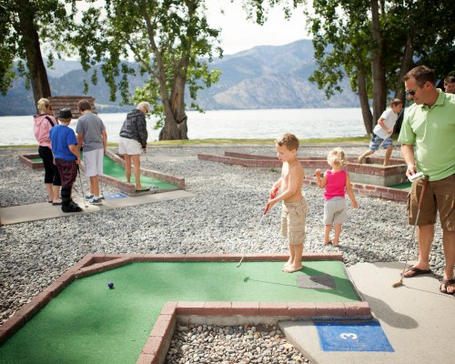 A GROUP OF PEOPLE PLAYING ON THE GOLF COURSE PUTTING GREEN.