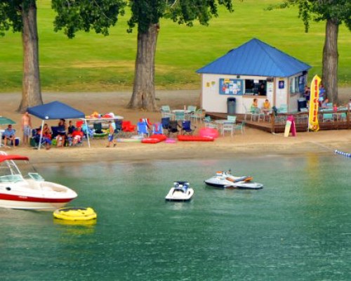 VIEW OF PEOPLE AT THE BEACH WITH BOATS.