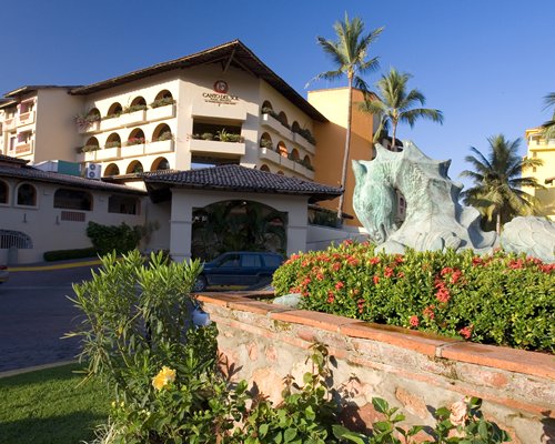 Exterior view of Canto del Sol with multiple balconies parking lot and palm trees.