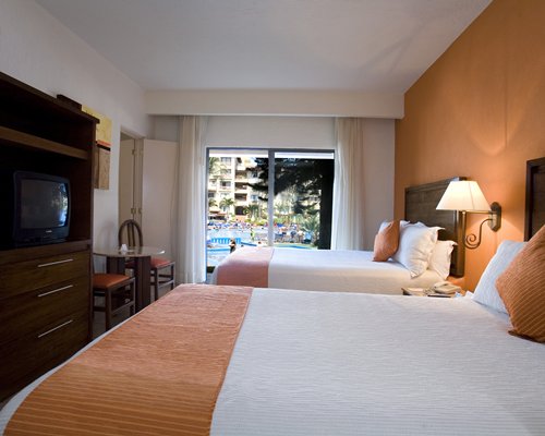 A well furnished bedroom with two beds television and an outside view.