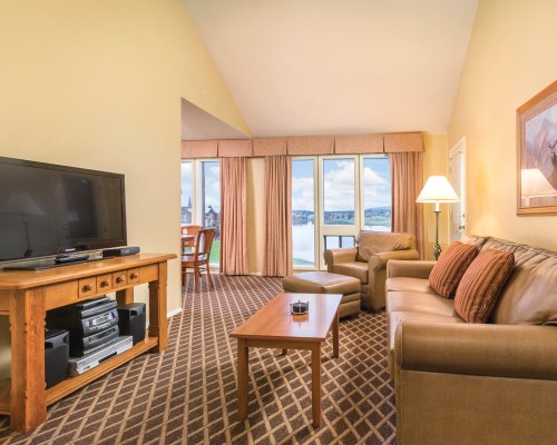 A WELL FURNISHED LIVING ROOM WITH A TELEVISION AND OUTSIDE VIEW.