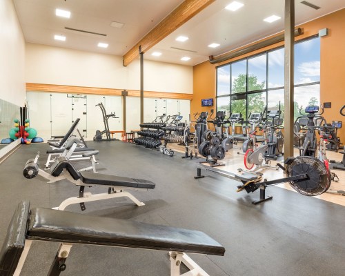 A WELL EQUIPPED INDOOR FITNESS CENTER WITH AN OUTSIDE VIEW.