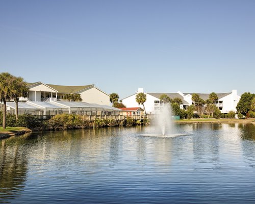Scenic exterior view of Wyndham Ocean Ridge alongside a lake with fountain.