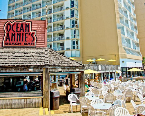 An outdoor bar with fine dining restaurant alongside multi story resort with private balconies.