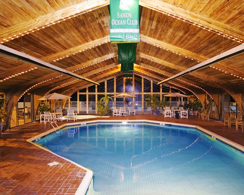 An indoor swimming pool with patio furniture.