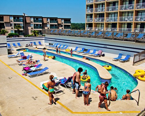 An outdoor swimming pool with chaise lounge chairs alongside the resort units.