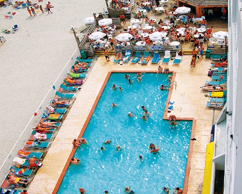 Outdoor swimming pool with chaise lounge chairs alongside outdoor restaurant.