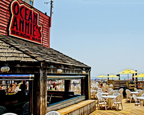 An outdoor bar with multiple dining tables and sunshades with ocean view.