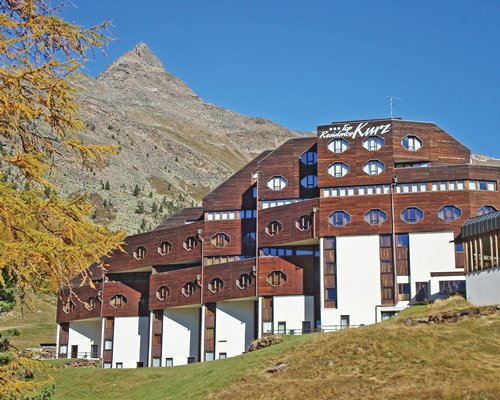 Exterior view of the multi story Top Residence Kurz resort alongside the mountains.