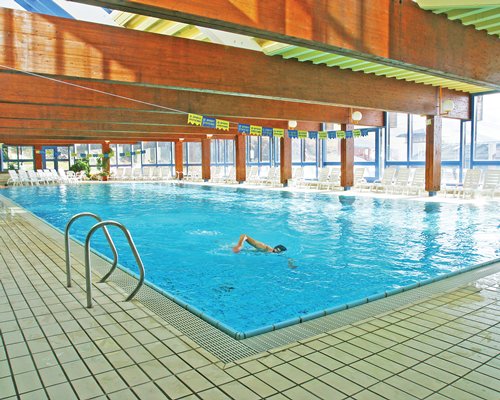 A large indoor swimming pool with chaise lounge chairs.