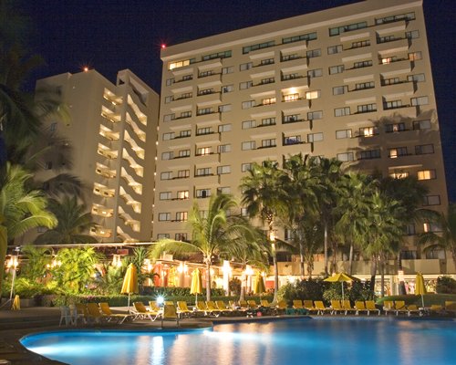 An outdoor swimming pool alongside the resort units at night.