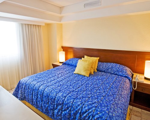A well furnished bedroom with a queen bed and outside view.