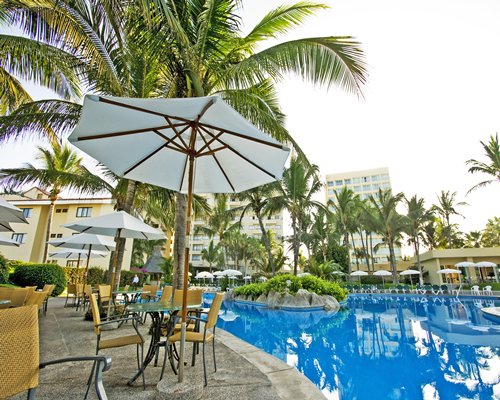 Exterior view of Mayan Sea Garden with outdoor swimming pool sunshades and palm trees.