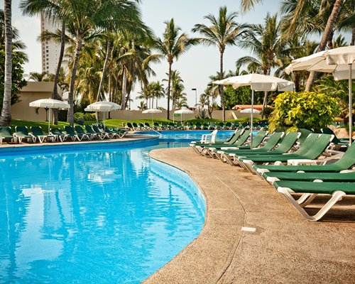 Outdoor swimming pool with chaise lounge chairs and sunshades.