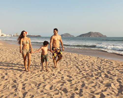 A family walking in the beach alongside the ocean.