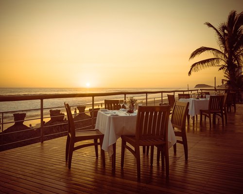 An outdoor restaurant alongside ocean at dusk.