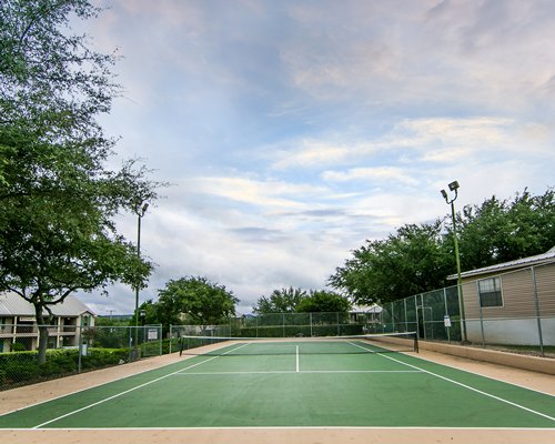 A resort tennis court with lighting near units.