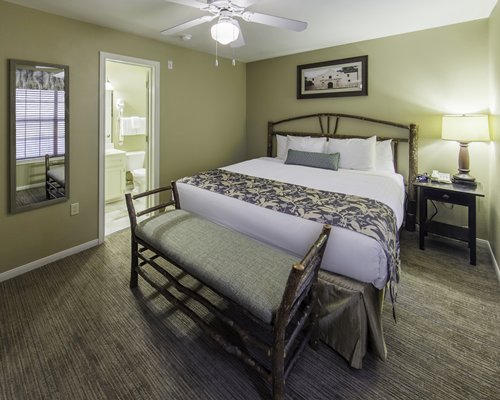 A view of a bedroom with a large bed and bathroom door.