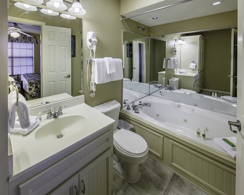 A bathroom with single sink vanity and bathtub with shower.