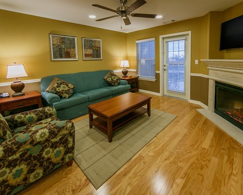 A well furnished living room with television fireplace and balcony view.