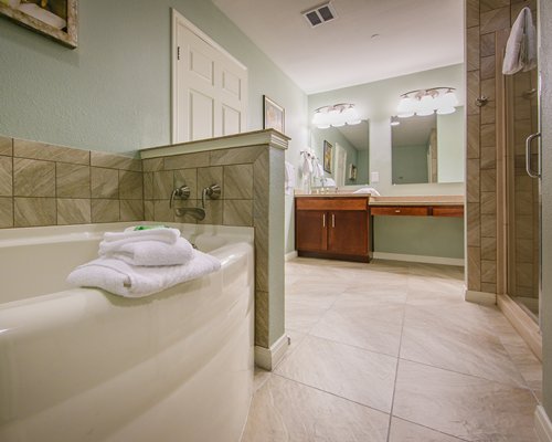 A large bathroom vanity with bathtub and shower stall.