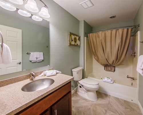 A bathroom with single sink vanity and bathtub shower.