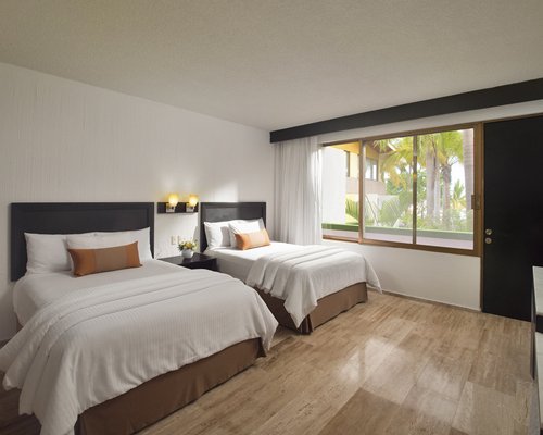 A well furnished bedroom with two twin beds television and outside view.