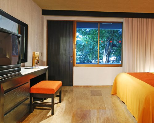 A well furnished bedroom with television and an outside view.