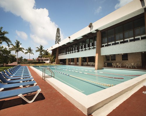 An outdoor swimming pool with chaise lounge chairs surrounded by trees.