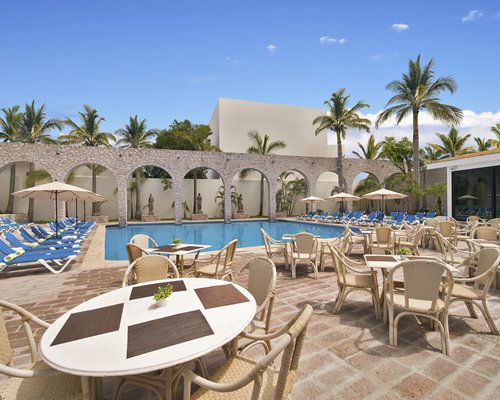 Outdoor swimming pool with chaise lounge chairs and pool side bar alongside multiple unit balconies.