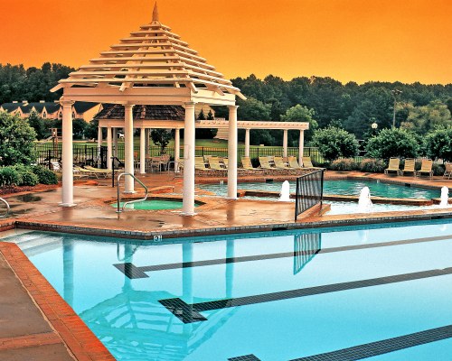 A VIEW OF OUTDOOR SWIMMING POOL AND HOT TUB WITH CHAISE LOUNGE CHAIRS.