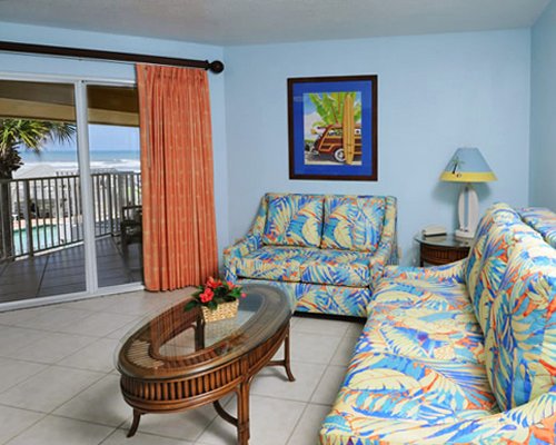 A well furnished living room with a balcony and beach view.
