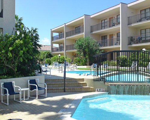 An outdoor swimming pool and patio chairs alongside the resort condos.