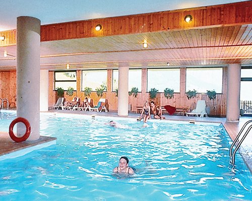An indoor large swimming pool with chaise lounge chairs.