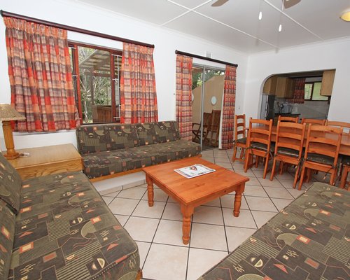 A well furnished living room with dining area open plan kitchen and patio.