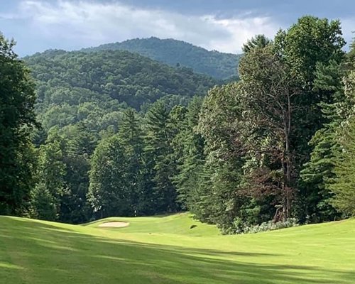 Golf course surrounded by wooded area.