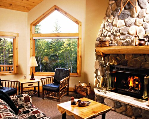 A well furnished living room with fire in the fireplace and outside view.