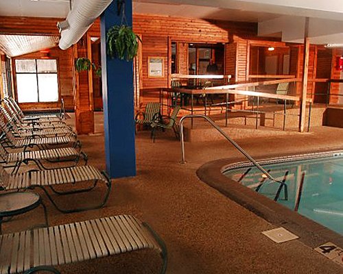 An indoor swimming pool with chaise lounge chairs.