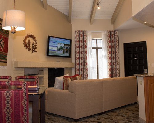 An open plan living room with a sofa glass top dining and kitchen area.