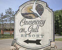 Exterior view of a unit with wooden patio at Causeway on Gull surrounded by wooded area.