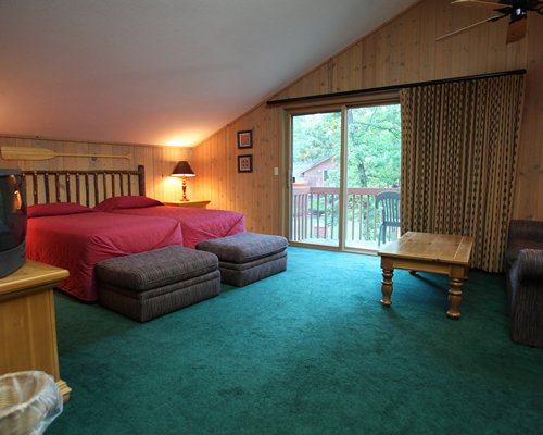 A well furnished bedroom with two queen beds television and balcony.