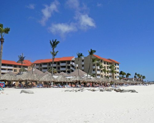 A view thatched sunshades alongside multi story resort units.