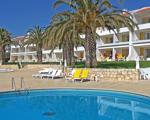 An outdoor swimming pool with chaise lounge chairs alongside the resort units.