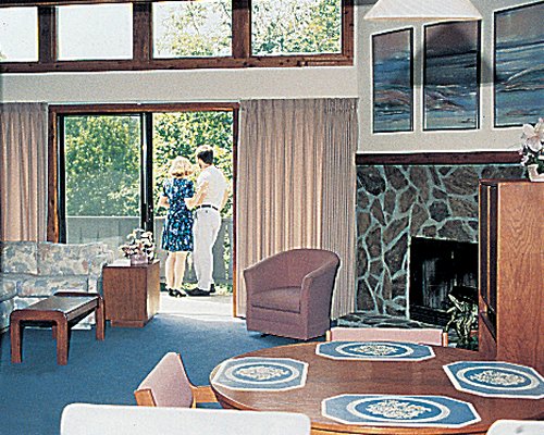 A well furnished living room with a fireplace wooden dining area and patio.
