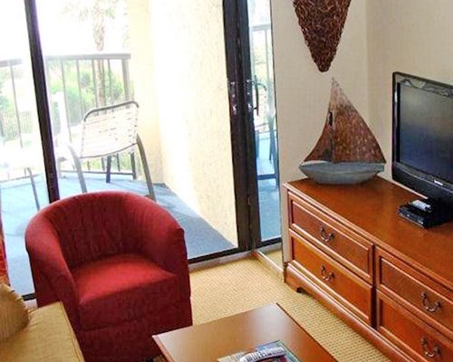 A well furnished living room with a television and balcony with patio furniture.