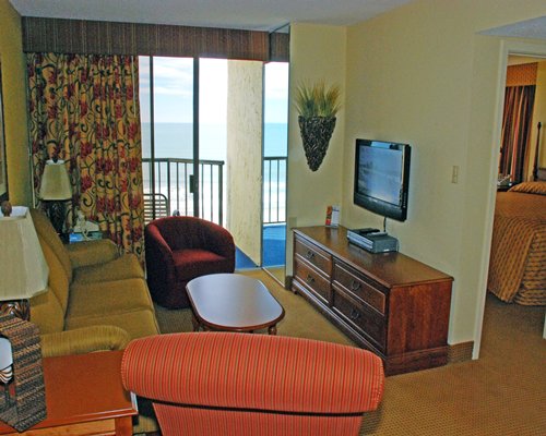 A well furnished living room with television balcony and view of bedroom.