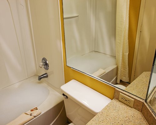 A bathroom with a bathtub shower and mirror.