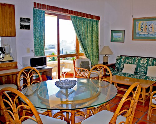 A well furnished living room with dining area open plan kitchen and balcony.