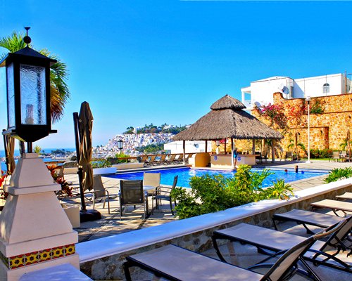 Outdoor swimming pool with chaise lounge chairs and thatched sunshade.